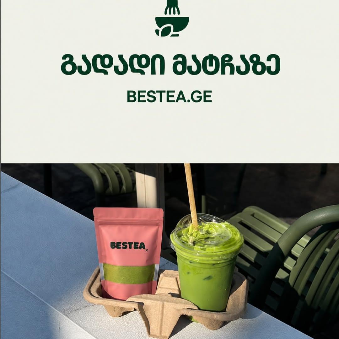 A pink BESTEA pouch with a green window beside a clear takeaway cup of bright green iced matcha with a paper straw, both in a cardboard cup carrier on a ledge